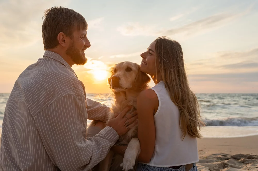 Young couple hanging out at the beach with their dog