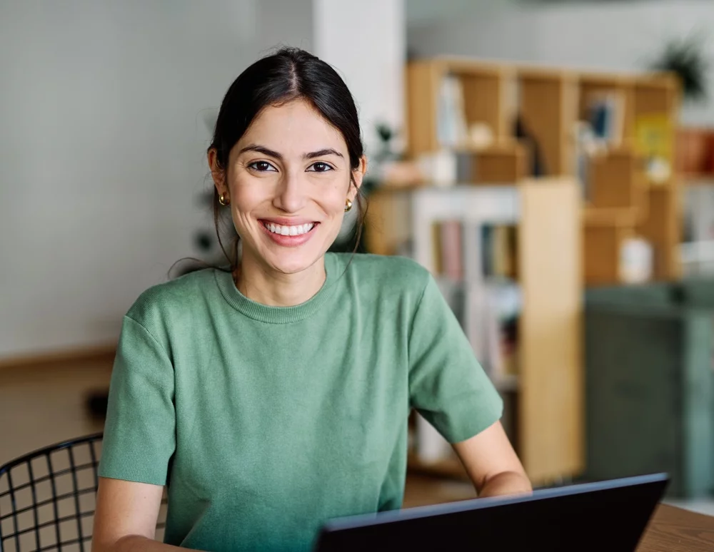 Smiling young girl using a laptop in the library