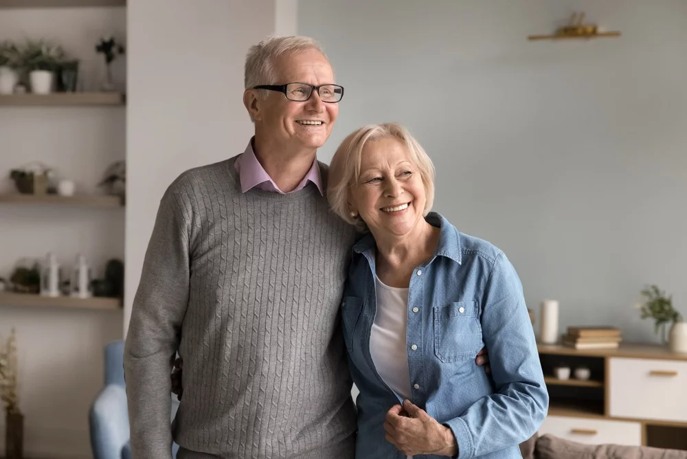 Senior couple holding each other, smiling in their home