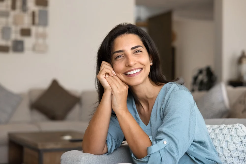 Smiling woman sitting comfortable on a couch in a home setting
