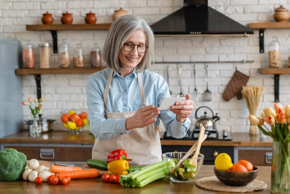 Older adult smiling in the kitchen preparing a recipe